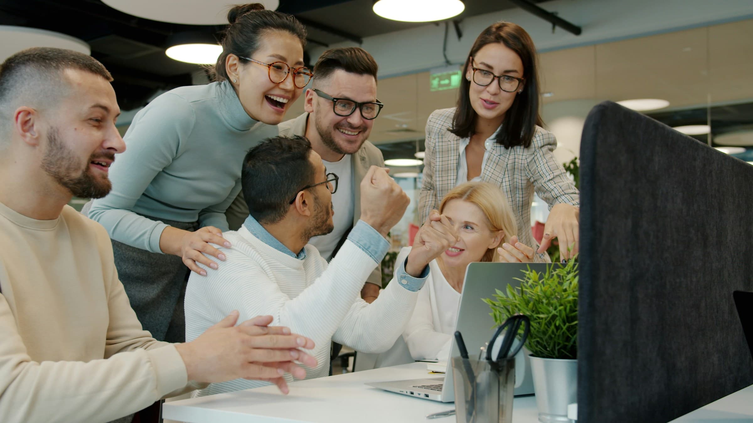 Team freut sich gemeinsam über einen Erfolg am Schreibtisch