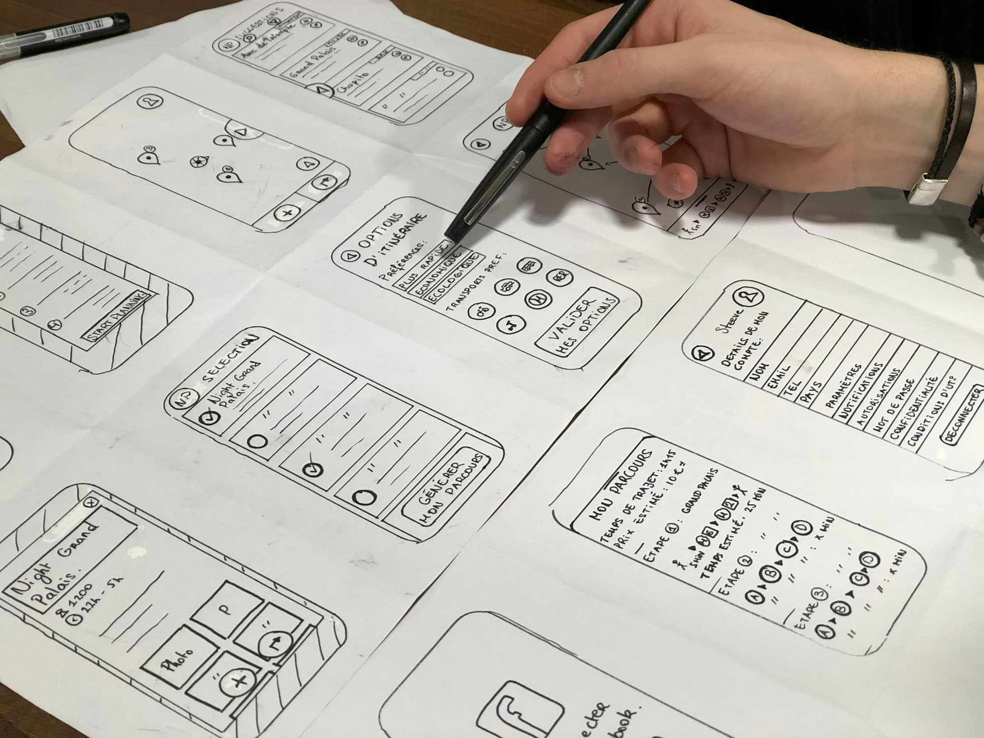 Hand mit Stift über Papierskizzen einer App