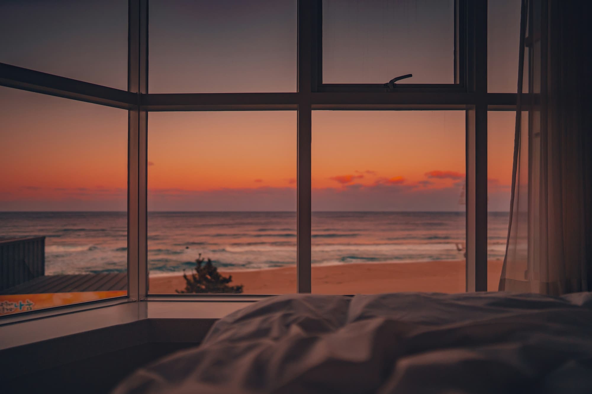 Silhouette einer Person am Fenster mit Blick auf das Meer bei Sonnenuntergang